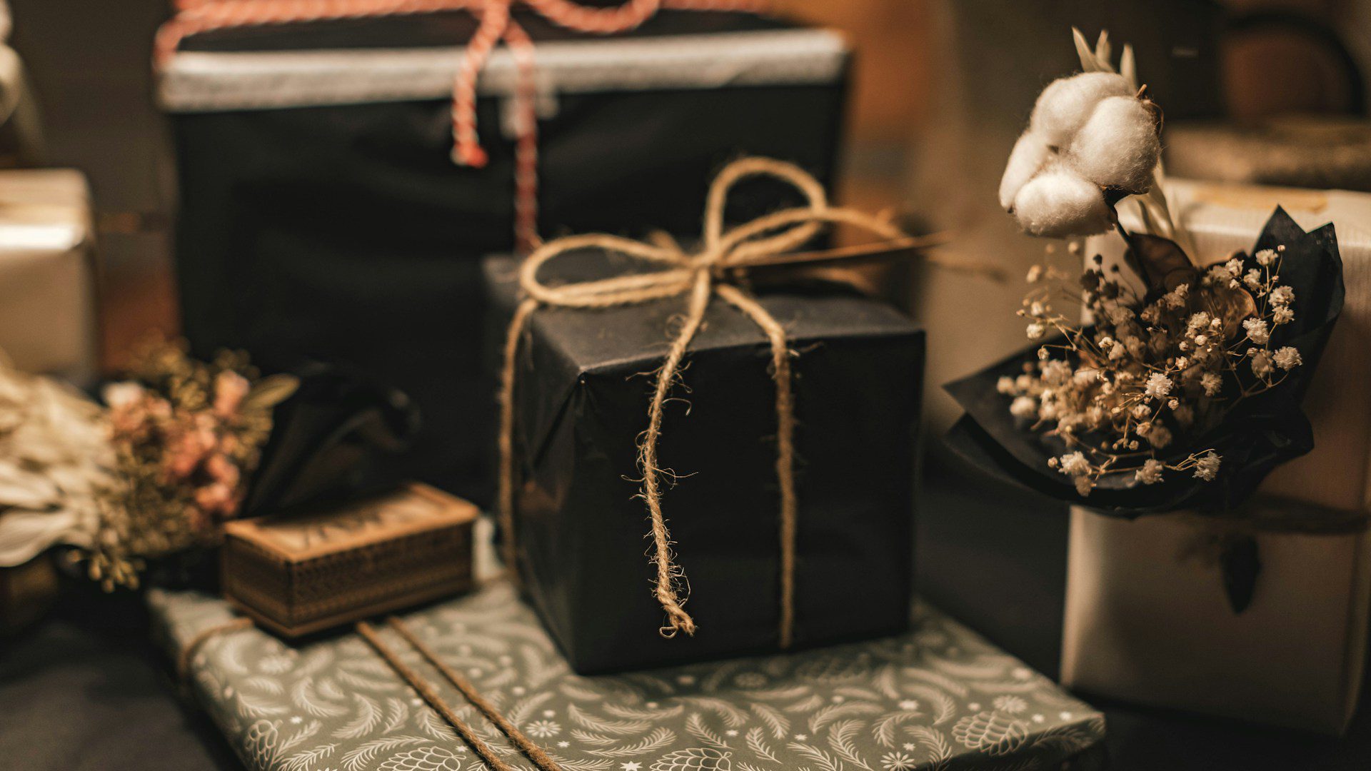A wrapped gift box rests on a black and white floral cloth.