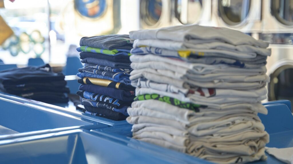 A neat stack of folded shirts on a blue table.