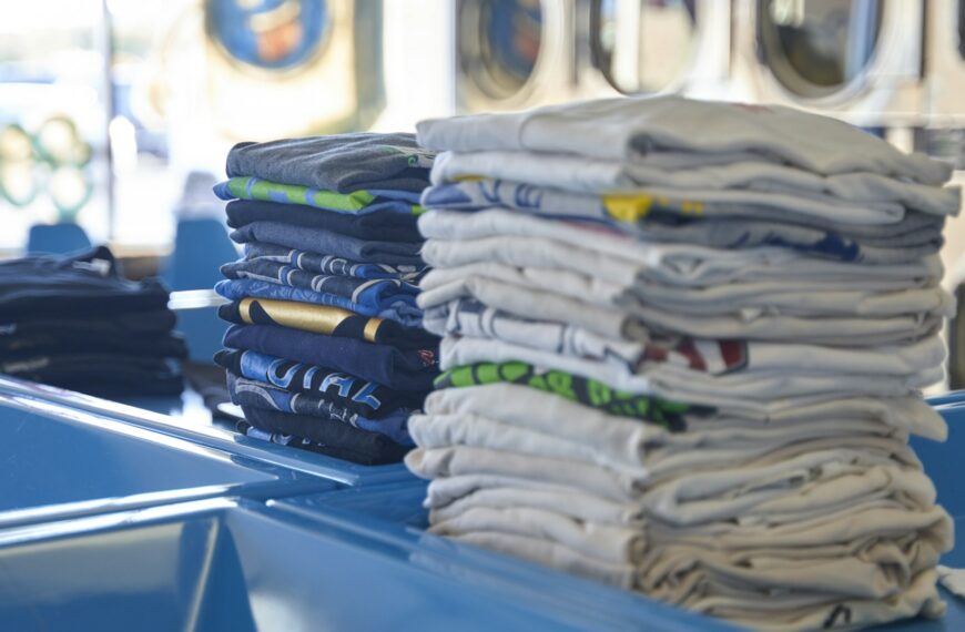 A neat stack of folded shirts on a blue table.