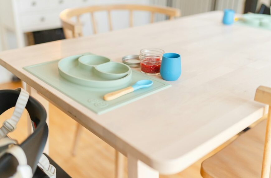 A table set with a bowl, plate and spoon for a toddler meal.