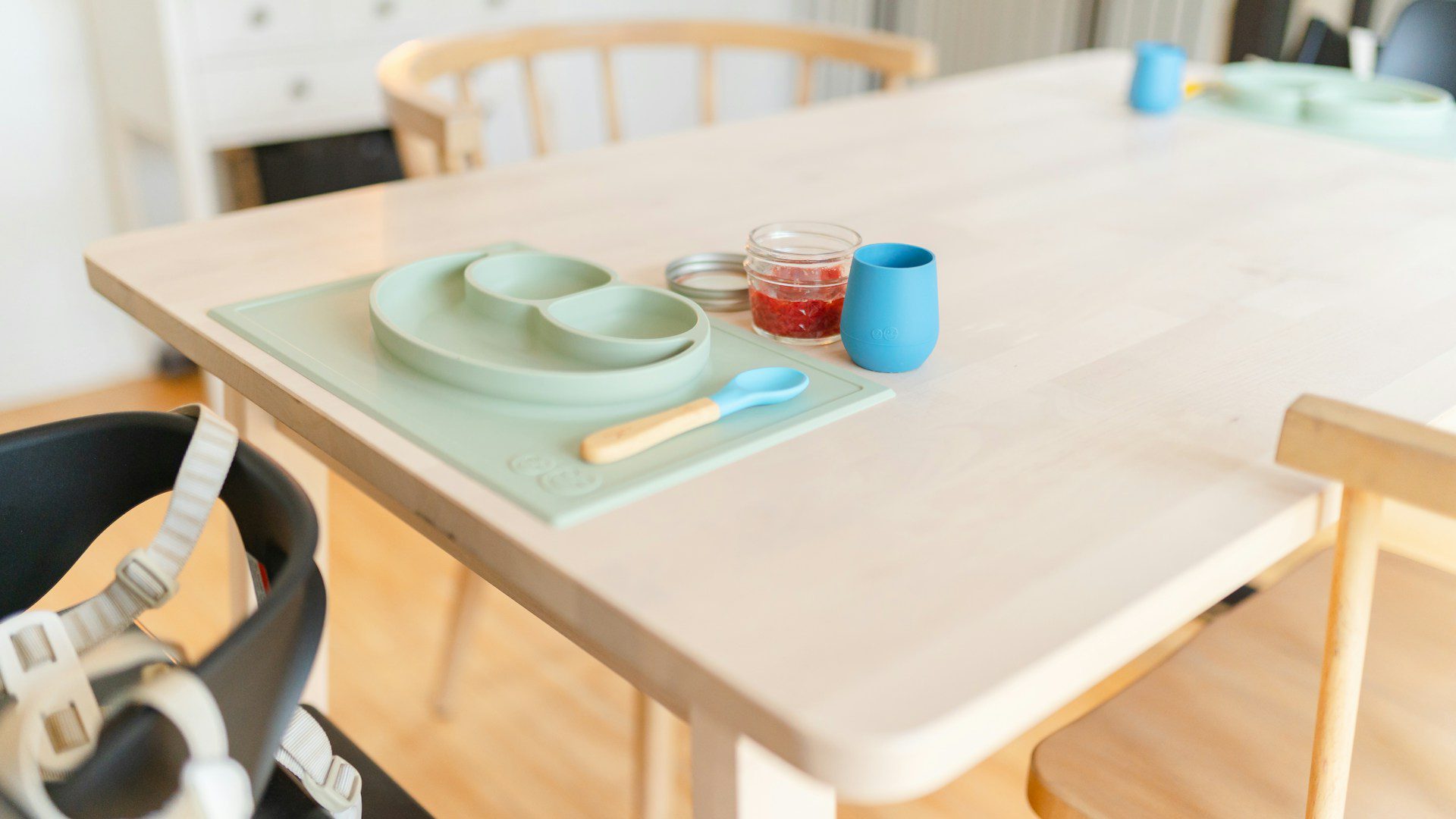 A table set with a bowl, plate and spoon for a toddler meal.
