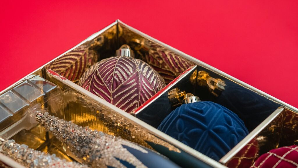 A box filled with Christmas ornaments sitting on a table.