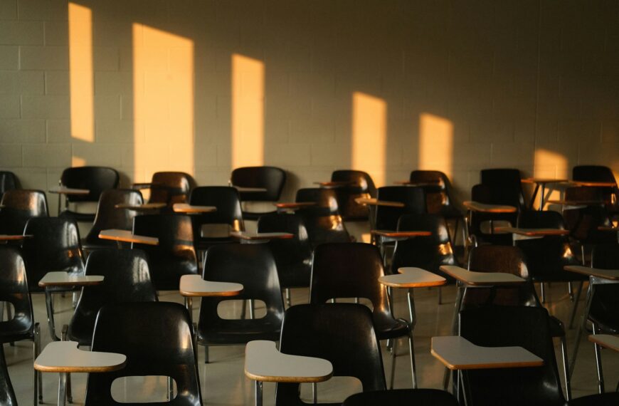 An empty classroom is lit by sunlight from the windows.