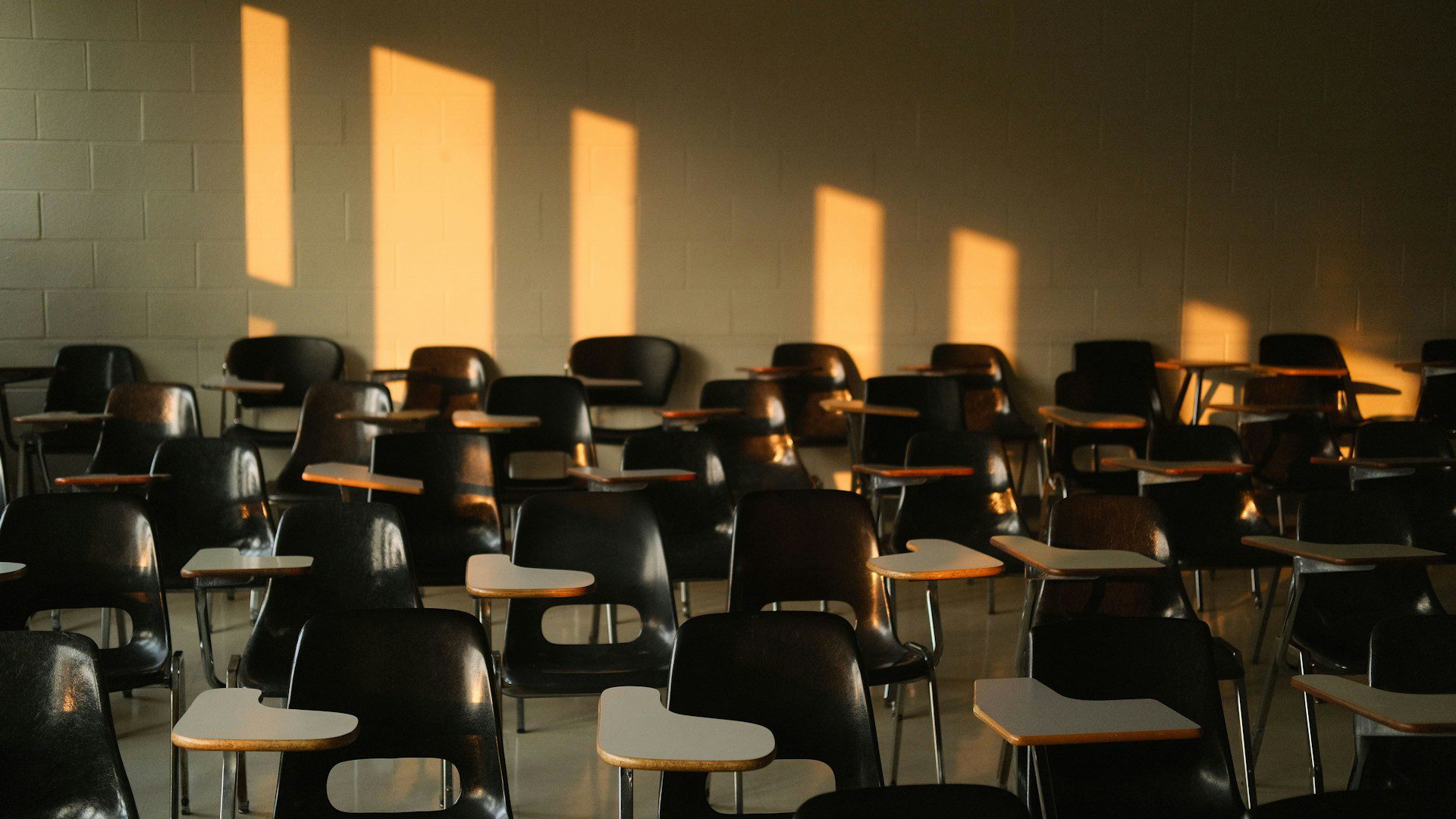 An empty classroom is lit by sunlight from the windows.