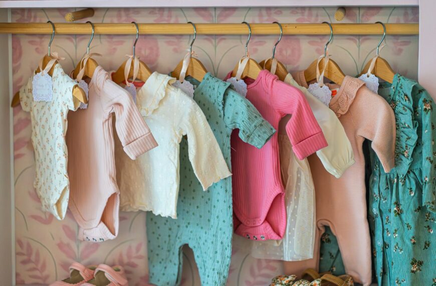 Small children's clothes hang on a rack above a row of shoes.