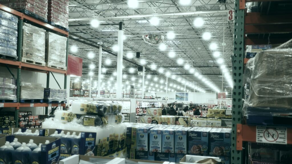 A wide aisle stretches through a brightly lit warehouse store.