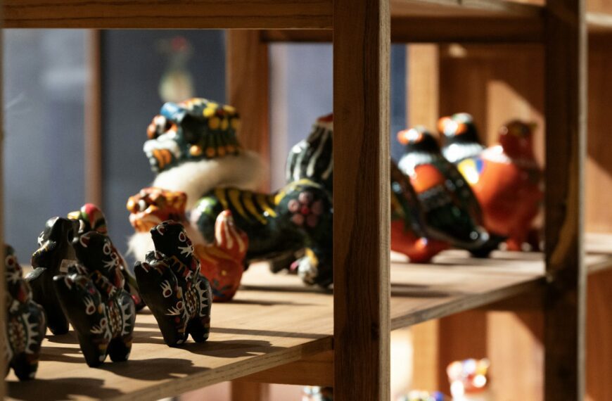 Colorful ceramic figurines displayed on wooden shelves.