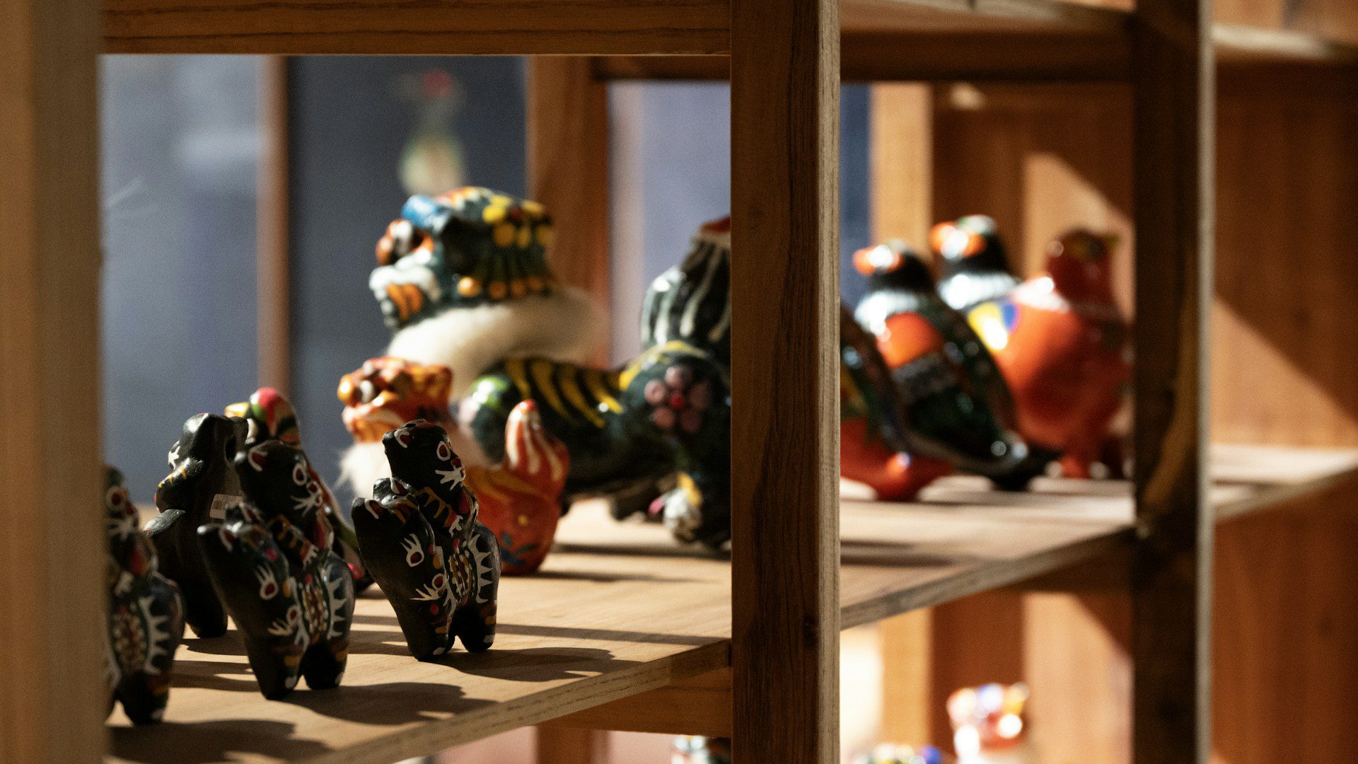 Colorful ceramic figurines displayed on wooden shelves.